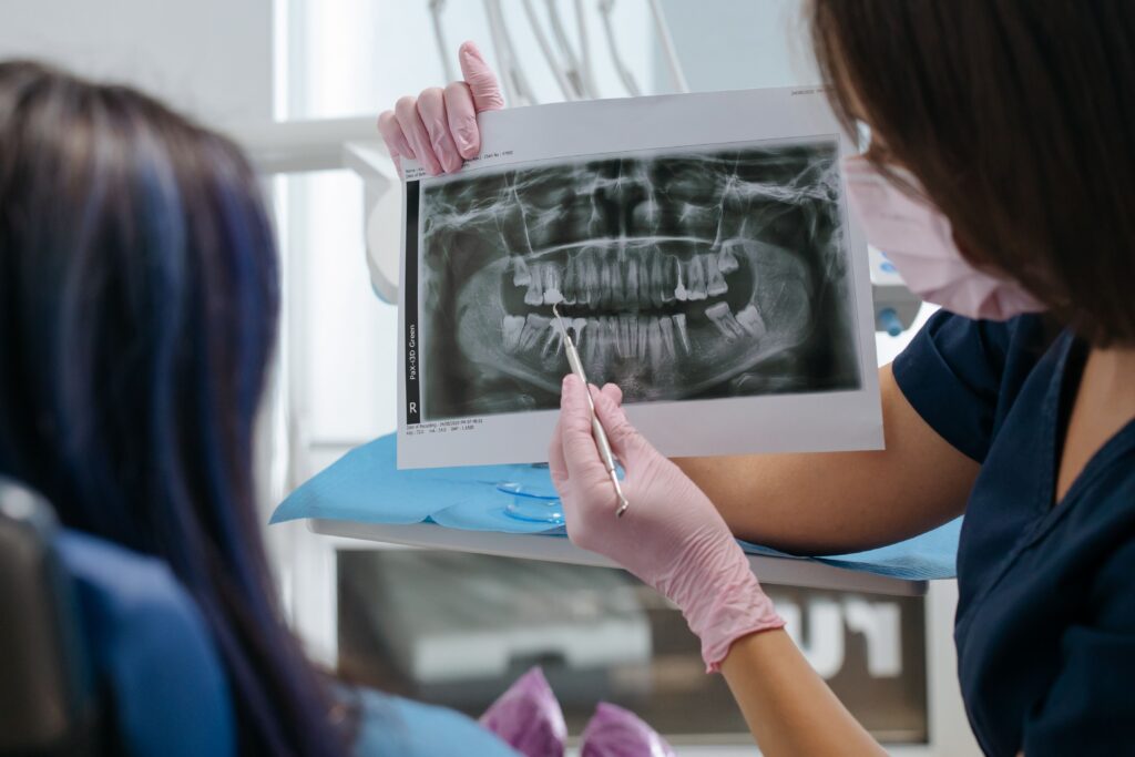 Dentist discussing whether a root canal or tooth extraction is the most appropriate treatment while reviewing a patient's dental X-rays during a consultation.